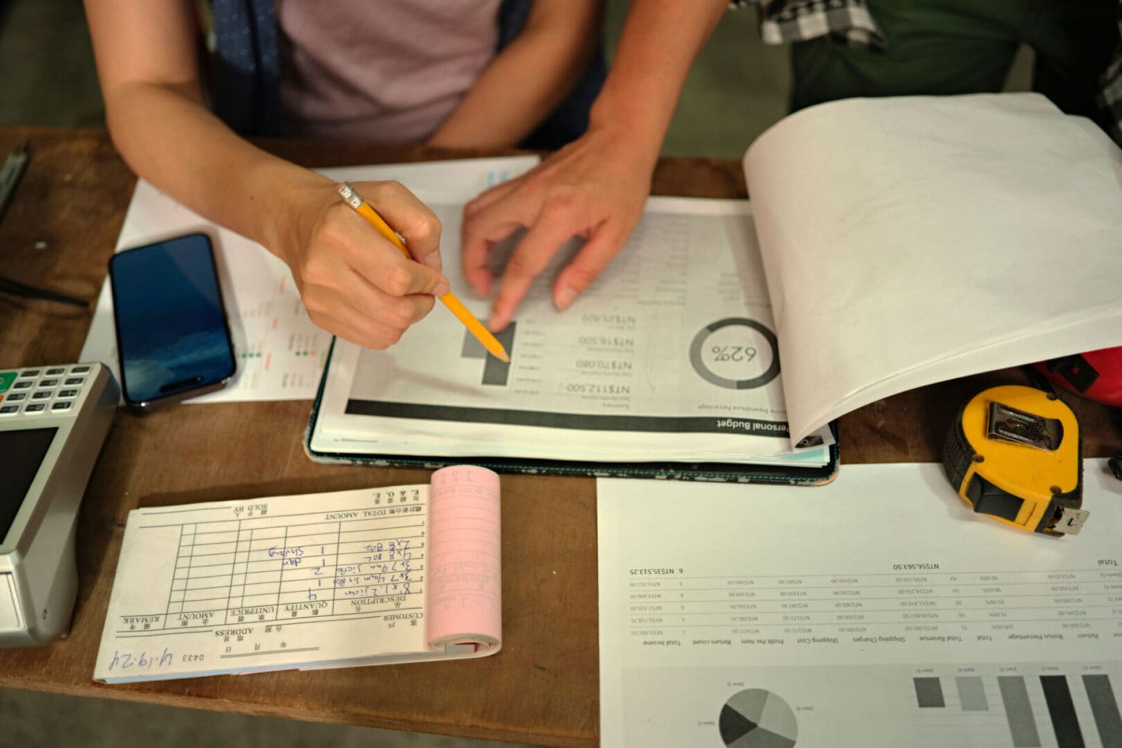Hands analyzing financial documents on a table.