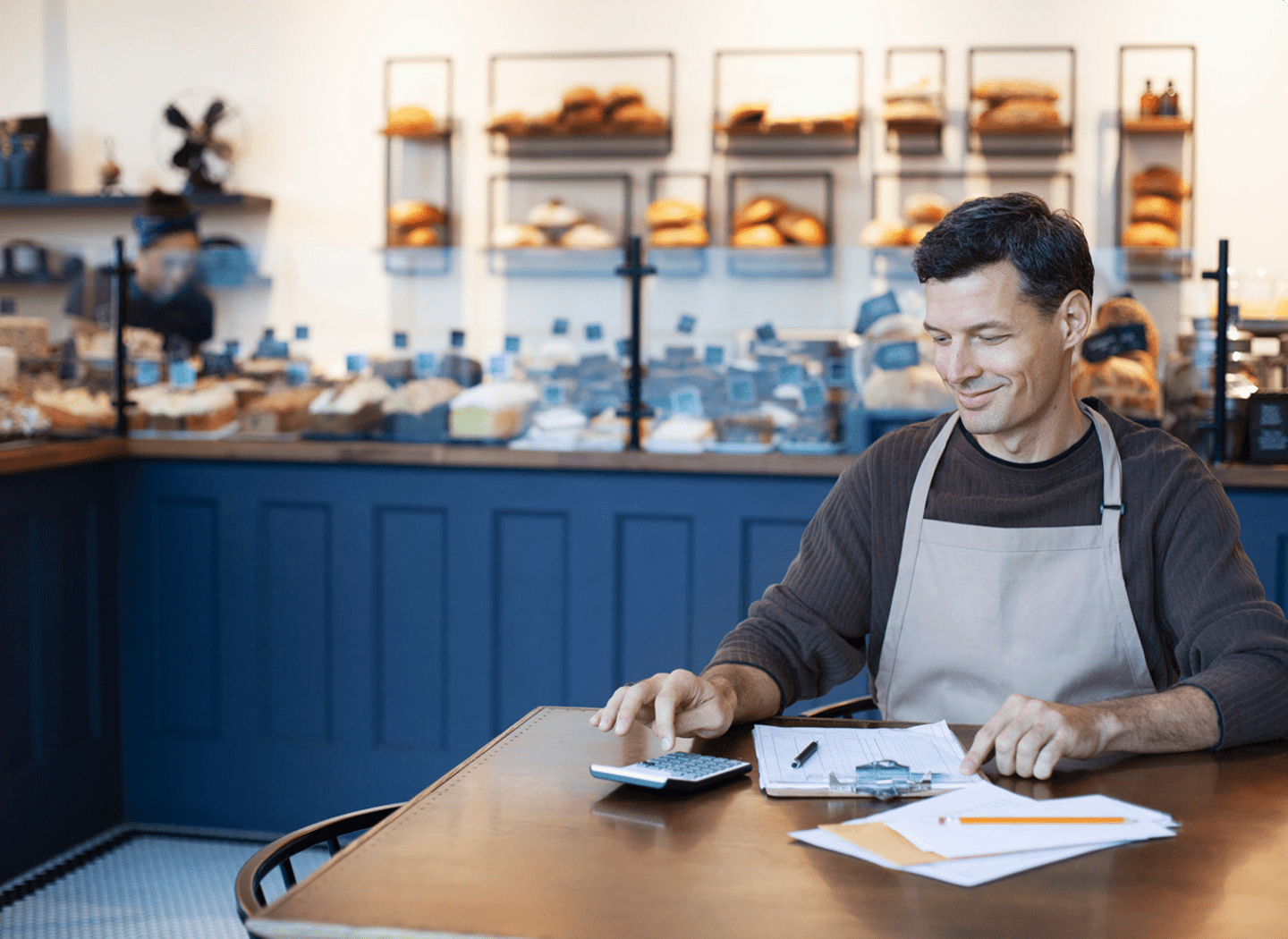 Bakery owner calculates finances at table.